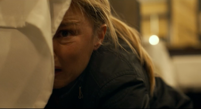 A woman fearfully peaking from behind something