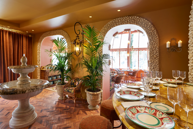 A restaurant decorated with tall plants and a water feature